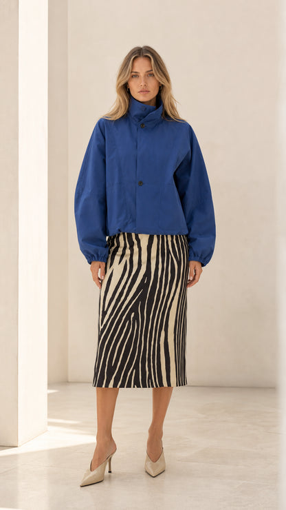 Front full view of woman wearing royal blue high neck cropped blouson jacket with zebra midi skirt