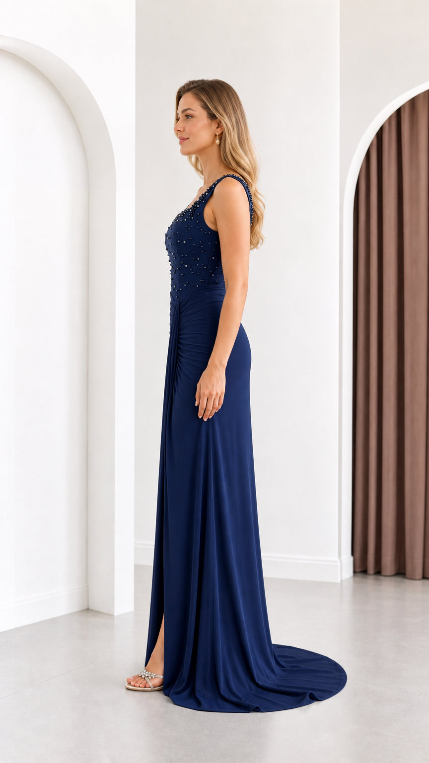 Side profile view of the navy blue ruched formal gown showing silhouette and draping