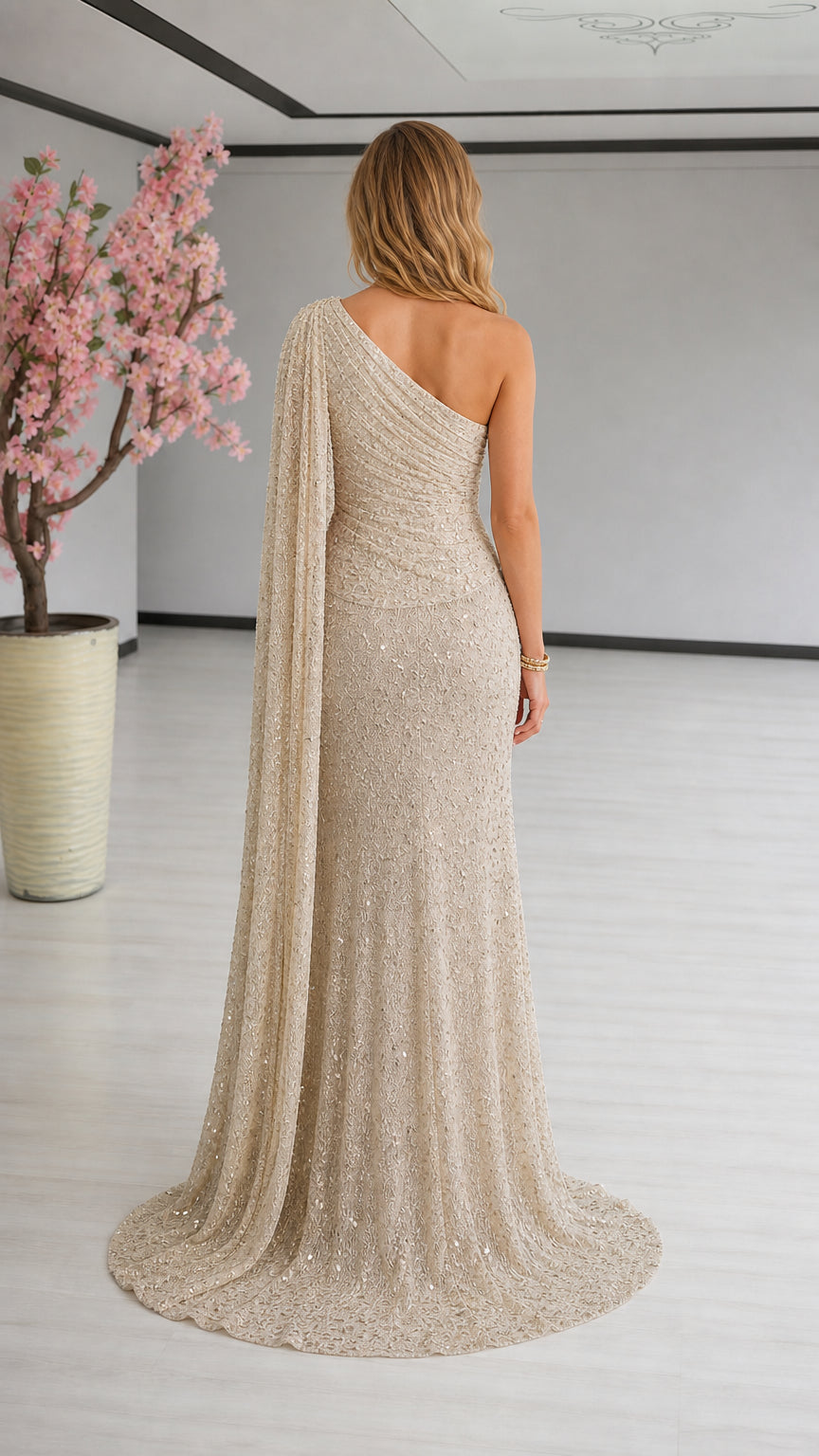 Back view of model in champagne one-shoulder evening gown with draped cape detail