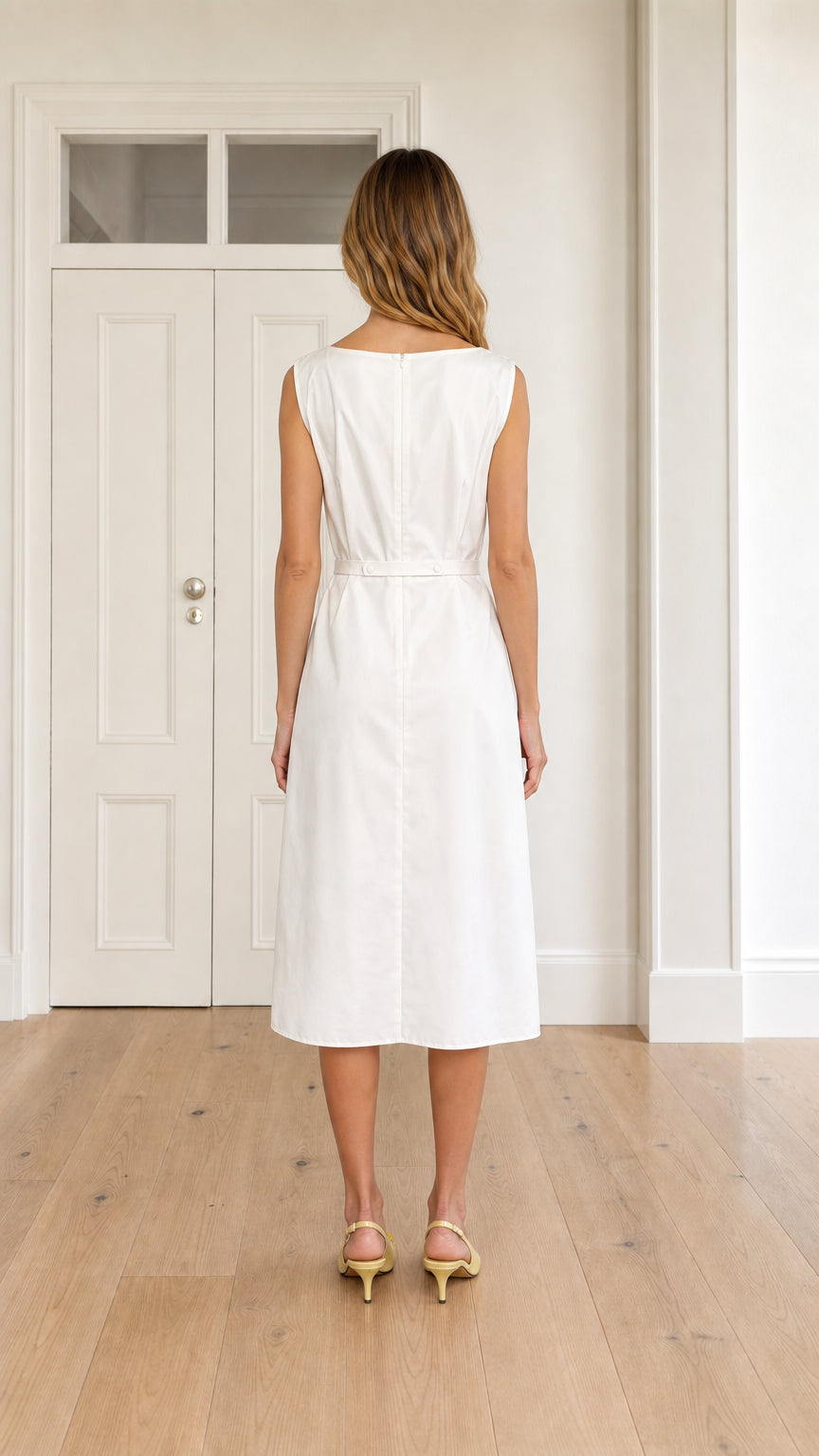 Back view of woman wearing white boatneck midi dress with clean back construction