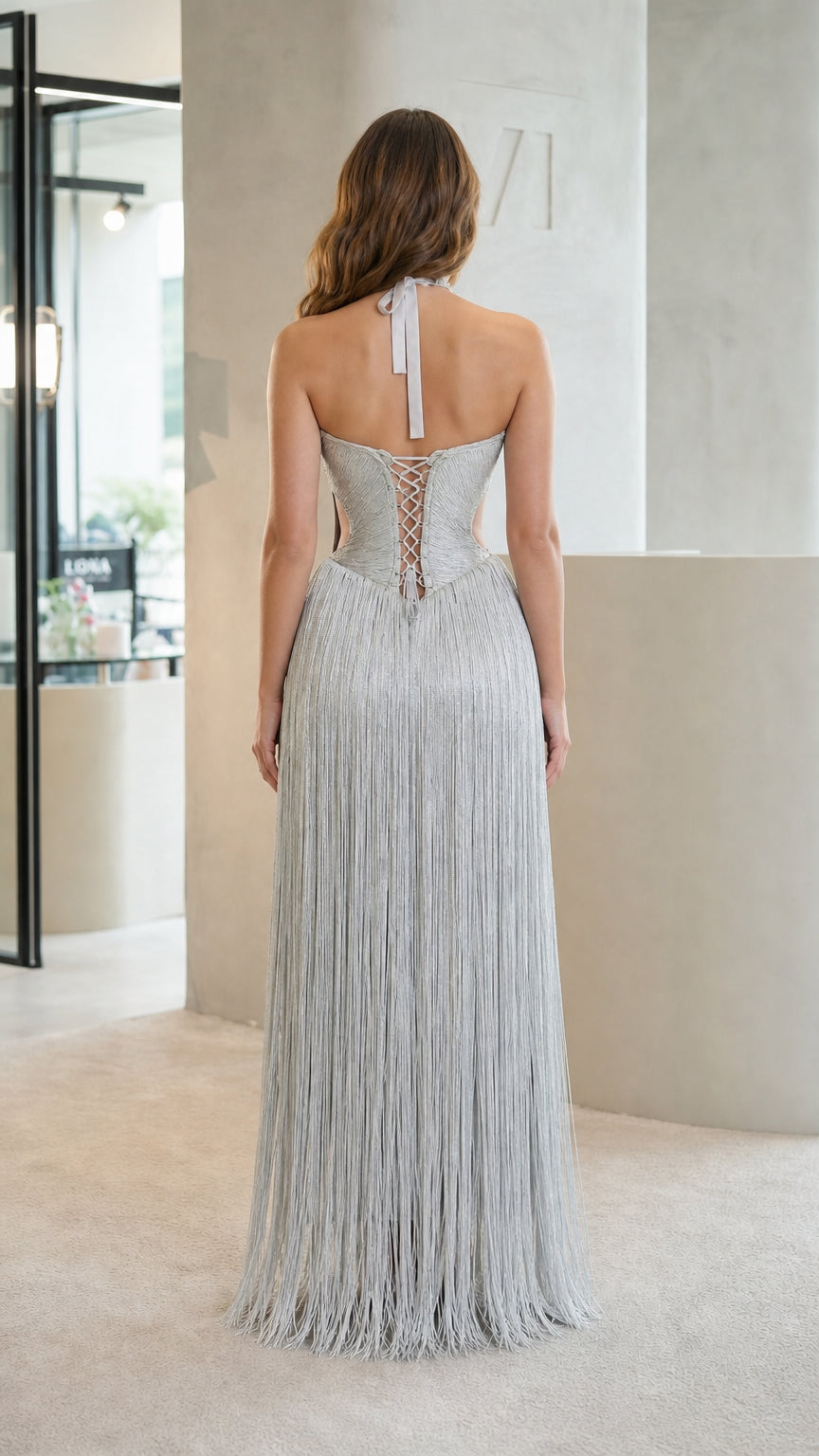 Back view of model showing lace-up corset back and halter tie on silver fringe gown