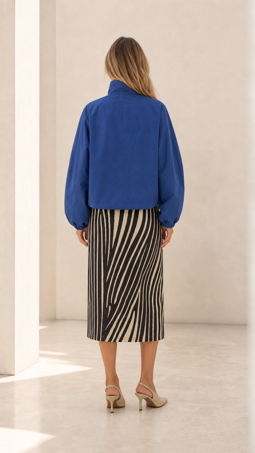 Back view of woman wearing royal blue cropped jacket with gathered sleeves