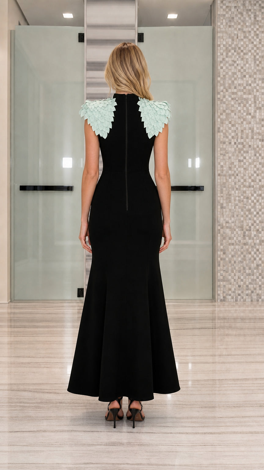Back view of black floor-length gown showing rear zipper closure and petal shoulders