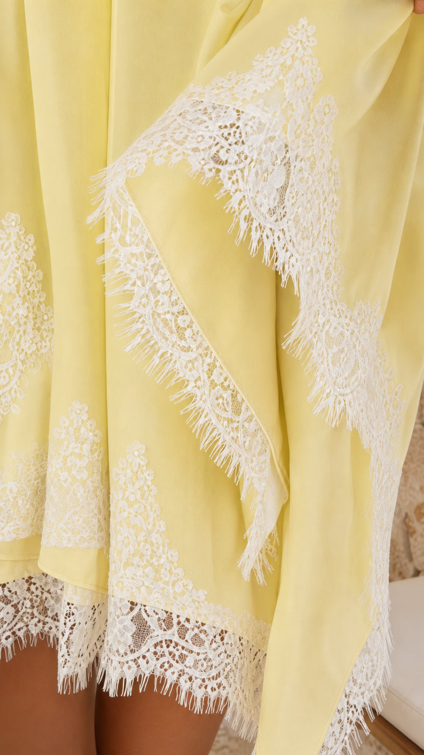 Close-up detail of white floral eyelash lace trim on pastel yellow fabric