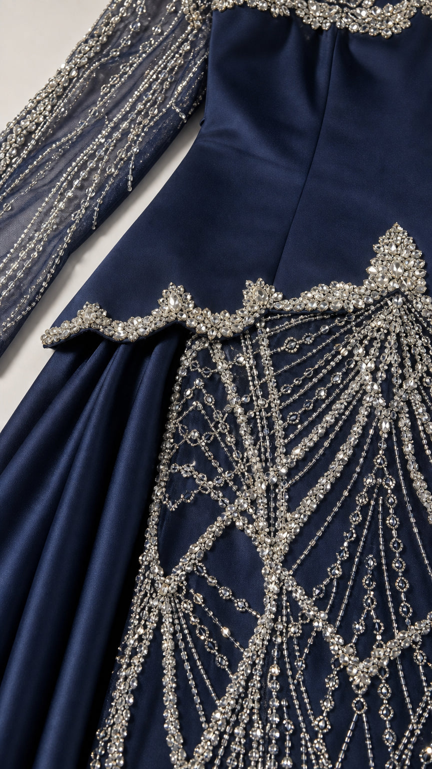 Close-up detail of intricate crystal beadwork and drop-waist overlay on navy gown
