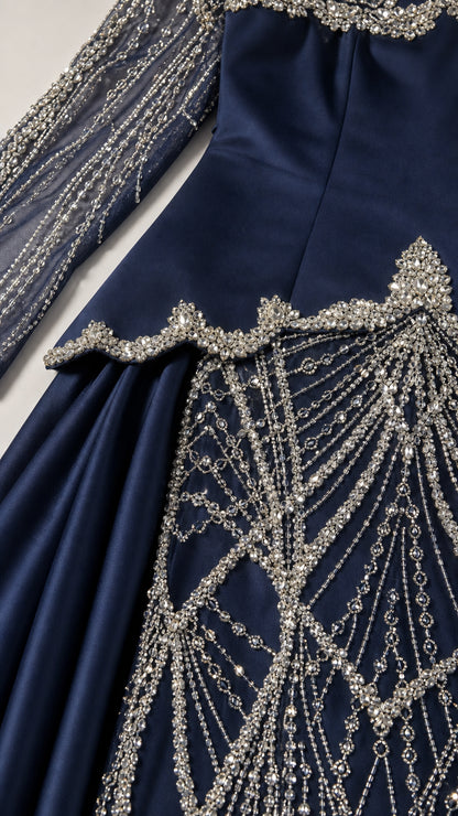 Close-up detail of intricate crystal beadwork and drop-waist overlay on navy gown