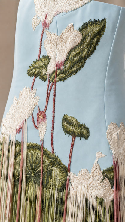 Close-up detail of botanical lotus flower and leaf embroidery on sky blue fabric
