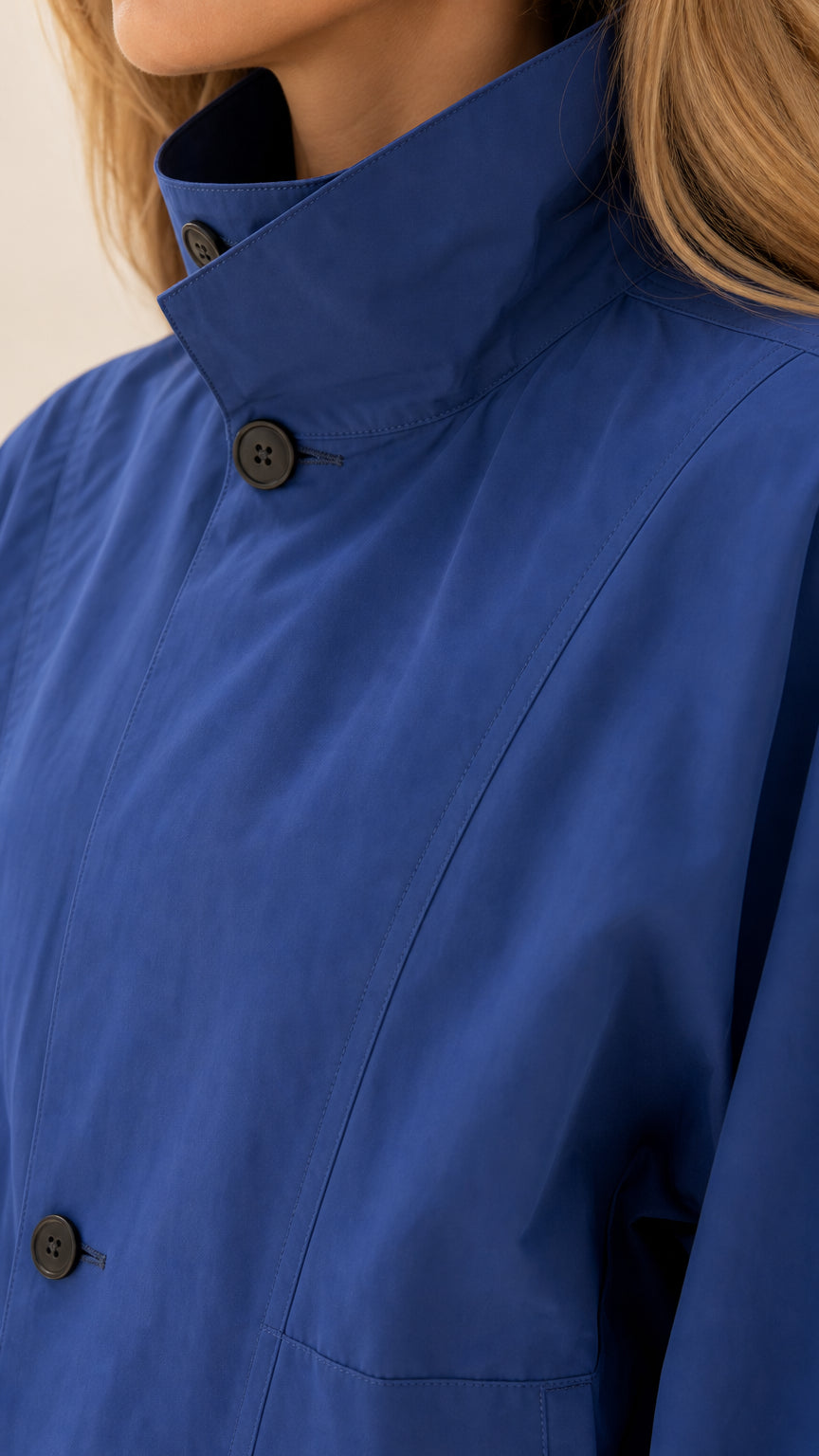 Close-up detail of high stand collar and button on royal blue blouson jacket
