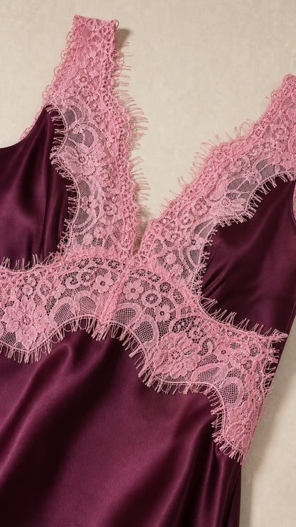 Close-up detail of delicate pink floral eyelash lace on lustrous burgundy satin
