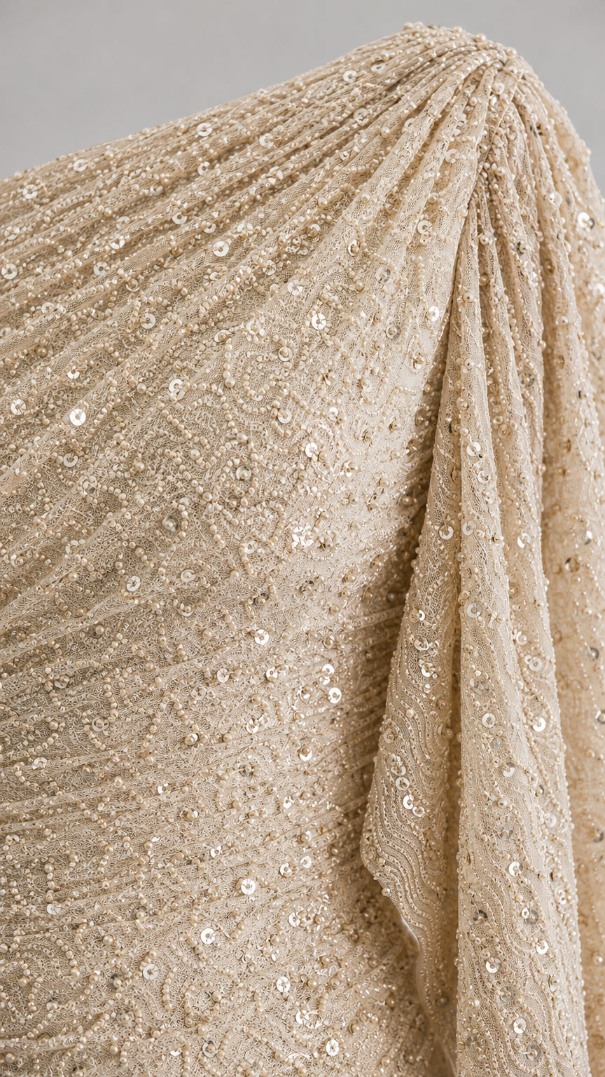 Close-up detail of textured champagne sequin and pleated fabric