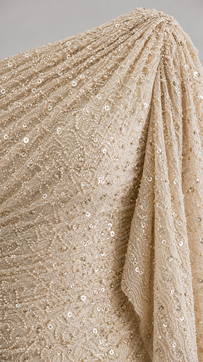 Close-up detail of textured champagne sequin and pleated fabric