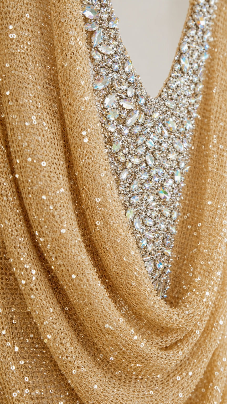 Close up detail of gold draped cowl fabric and crystal rhinestone embellishments