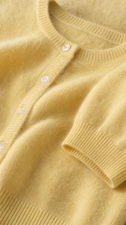 Close-up detail of pastel yellow fine knit texture, ribbed neckline and buttons