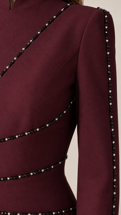 Close-up detail of burgundy dress fabric with diagonal crystal beaded piping