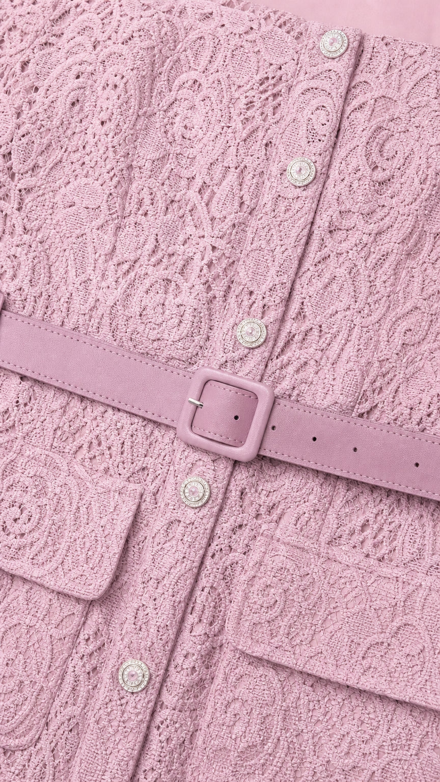 Close-up detail of textured pink lace fabric, decorative buttons, and matching buckle belt