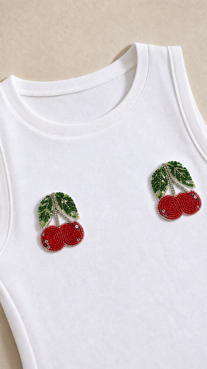Close-up detail of beaded cherry appliqués on white neckline
