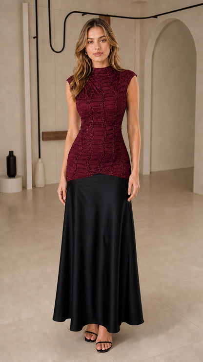 Front view of model wearing burgundy beaded bodice with black satin skirt maxi dress
